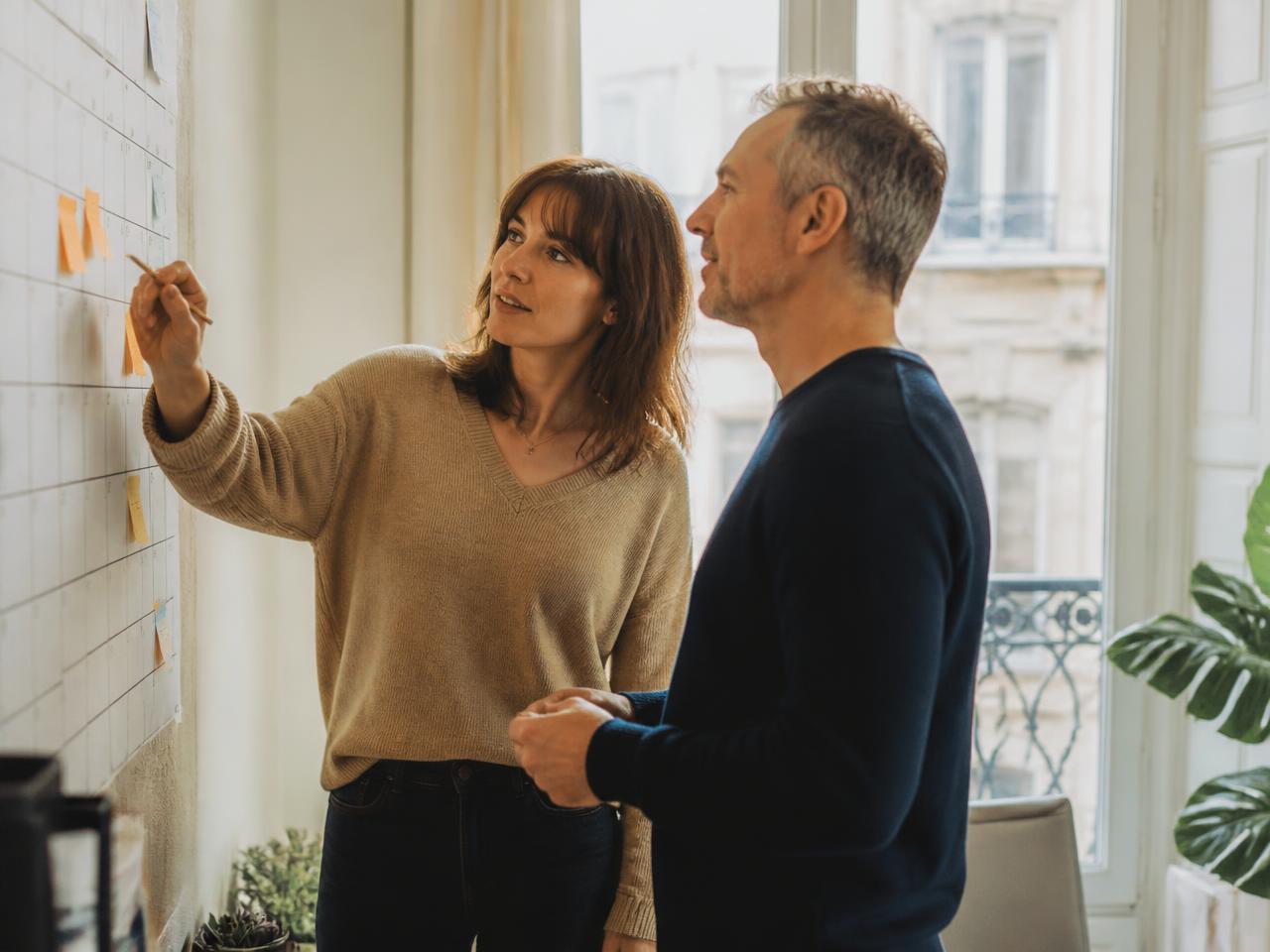 Deux collaborateurs planifient les entrées et sorties du personnel sur un calendrier mural